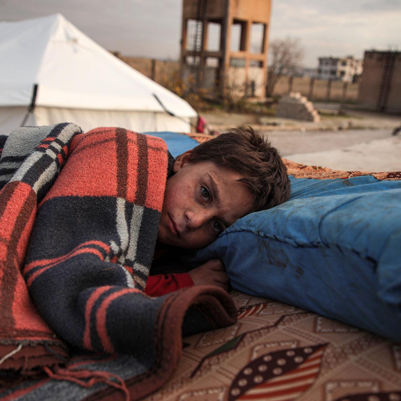 A Syrian child sleeps in the open at a displacement camp near Turkey’s border after fleeing from southern Idlib.