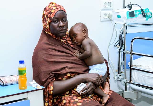 A Sudanese mother holds her young child at a medical facility in Sudan.